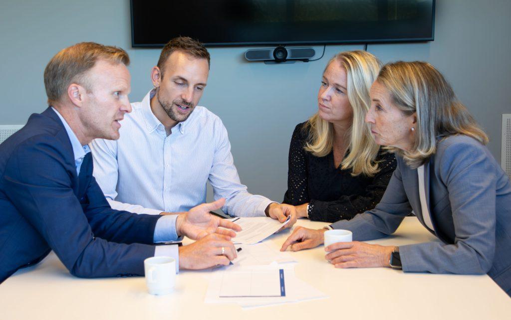Diskusjon mellom fire trenerne som sitter rundt et bord og ser på hverandre.